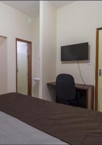 a bedroom with a bed and a desk and a television at BH EXPO SUITES & KITNETES in Belo Horizonte