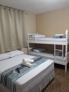 a room with two beds and two bunk beds at Pousada Dona Quiteria in Penha