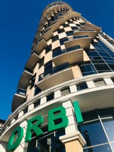 um edifício alto com um sinal verde em frente em Lina’s seaside apartments em Batumi