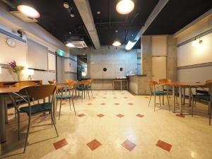uma sala de jantar com mesas e cadeiras e uma cozinha em Business Hotel Legato em Tóquio
