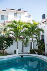 a swimming pool in front of a building with palm trees at Villa Lupita in Zihuatanejo