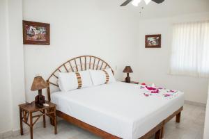 a bedroom with a large white bed with flowers on it at Villa Lupita in Zihuatanejo