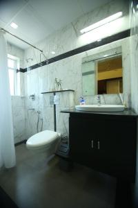 a bathroom with a toilet and a sink and a mirror at Omnest in Cochin