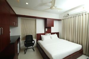 a bedroom with a bed and a desk and a chair at Omnest in Cochin