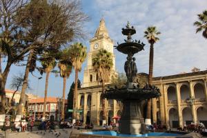 a fountain in front of a building with a clock tower at Nativa suites in Cochabamba