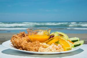a plate of food with fish and vegetables on the beach at Hotel Brisas de Verano in San Juan de Alima
