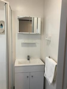 a white bathroom with a sink and a mirror at Peppermint Grove Beach Holiday Park in Capel