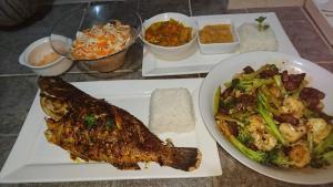 een tafel met twee borden voedsel met vis en groenten bij Carana Hilltop Villa in Glacis