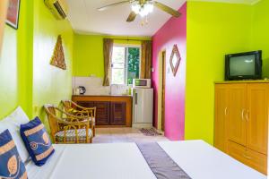 a room with a bed and a tv and a kitchen at Chez Charly Bungalow in Nai Yang Beach