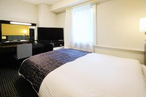 a bedroom with a bed and a desk and a window at APA Hotel Sapporo Susukino Ekimae in Sapporo