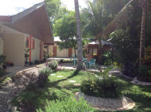 einen Garten mit Palmen und ein Haus in der Unterkunft Casa Paliton in Siquijor