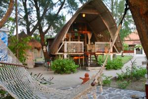 a hammock in front of a small house at Villa Sunset Beach in Gili Trawangan