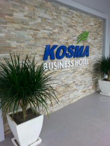 Kosma Business Hotel في كُوانتان: يوجد علامة على مبنى يوجد أمامه اثنين من النباتات الفخارية