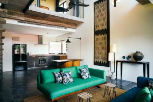 a living room with a green couch and a kitchen at Urban Residences - Siem Reap in Siem Reap