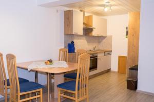 a kitchen with a wooden table and chairs and a kitchen with a stove at Landurlaub Eichinger in Thurmansbang