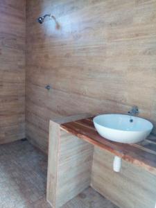 baño con lavabo blanco en una encimera de madera en Lakey Beach Inn hotel en Huu