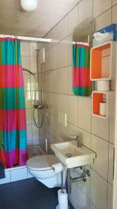 y baño con lavabo y cortina de ducha de arco iris. en b&b krättli, en Eggiwil 15 fotos más