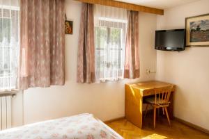 a bedroom with a desk and a tv on the wall at Casa Matie in Selva di Val Gardena