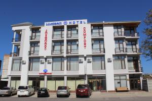 un edificio blanco con coches estacionados frente a él en Hotel Comfort en Kutaisi