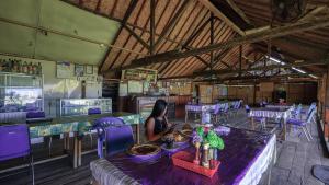a woman sitting at a table in a room with purple chairs at Lakey Beach Inn hotel in Huu