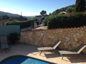 twee stoelen en een zwembad naast een stenen muur bij appartement en rez de villa in Gattières