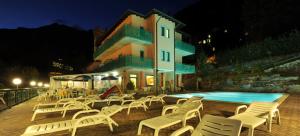 a group of white chairs next to a swimming pool at Hotel Torre in Sondalo