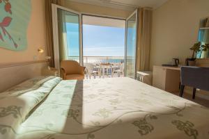 a bedroom with a bed with a view of the ocean at Savoy Hotel in Marina di Pietrasanta