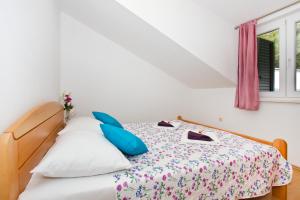ein Schlafzimmer mit einem Bett mit blauen Kissen und einem Fenster in der Unterkunft Villa Omis Michy - family house for big and small groups in Omiš