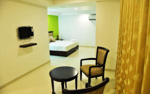 a bedroom with a bed and two chairs and a tv at Temple Plaza Kochi in Chottanikara