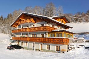 dom w śniegu z samochodem przed nim w obiekcie Pension Hochkönigblick w mieście Sankt Johann im Pongau