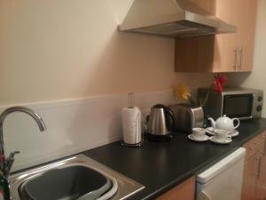 a kitchen counter with a sink and a microwave at Blueberry Two Bedroom Suite for 1, 2 or 3 people in Douglas