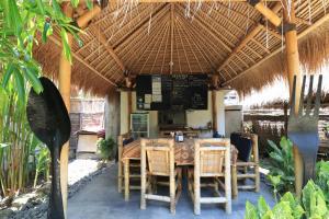 un restaurante con mesa y sillas bajo un techo de paja en Albany Home Stay, en Kuta Lombok