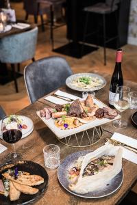 een houten tafel met borden eten en een fles wijn bij 't Goude Hooft in Den Haag