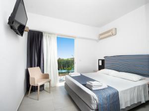 a bedroom with a bed and a tv and a window at Lymberia Hotel in Faliraki +50 photos