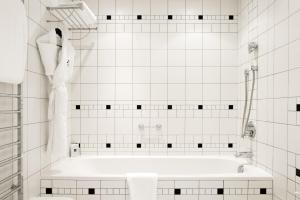 a white tiled bathroom with a bath tub at L'Agapa Hôtel - Spa Codage in Perros-Guirec