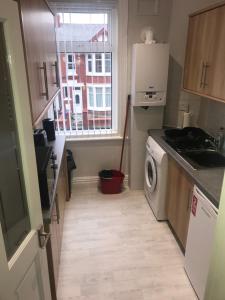 a kitchen with a washing machine and a window at Cornwall Apartments in Blackpool