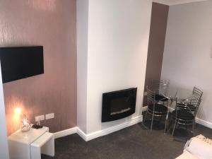 a living room with a fireplace and a table and chairs at Cornwall Apartments in Blackpool