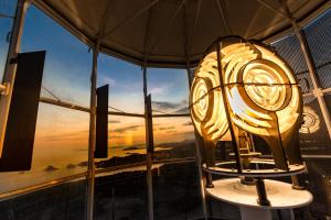 a clock in front of a window with a sunset at Faro Capo Spartivento in Chia
