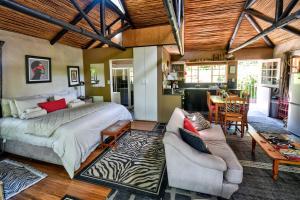 een slaapkamer met een groot bed en een woonkamer bij Maple Grove in Hogsback