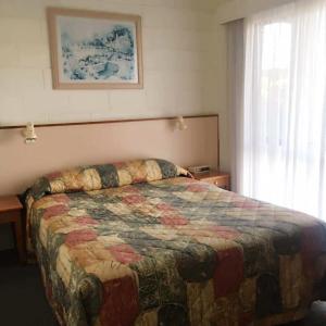 a bedroom with a bed with a quilt on it at Black Swan Motor Inn in Lakes Entrance