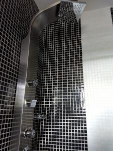 a shower with black tiled walls and a glass door at Dalarna Små Hotell in Punta del Este