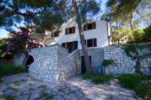 Biały dom za kamienną ścianą w obiekcie Villa Avelina w miejscowości Mali Lošinj