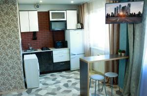 ビイスクにあるАпартаменты "Добрые Сутки" на Мартьянова 63のキッチン(白い家電製品、テーブル、スツール付)