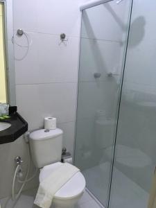 uma casa de banho com um WC e uma cabina de duche em vidro. em Pousada Tambaú em João Pessoa