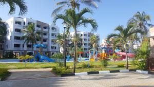 un parque infantil en un complejo con palmeras y toboganes en The Sultan Palace en Mombasa