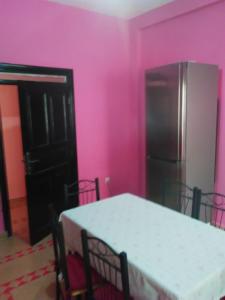 - une cuisine aux murs roses avec une table et un réfrigérateur dans l'établissement Riad Marrakech Ourika, à Marrakech