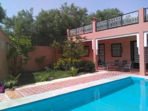 a villa with a swimming pool in front of a house at Riad Marrakech Ourika in Marrakesh