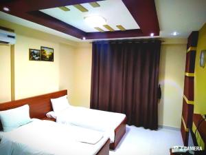 a room with two beds and a curtain at Al Mabila Hotel in Seeb