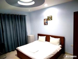 1 dormitorio con cama y pared azul en Al Mabila Hotel, en Seeb