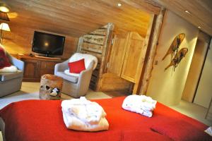 een slaapkamer met een bed, een tv en een stoel bij Hôtel Chalet Alpage in La Clusaz